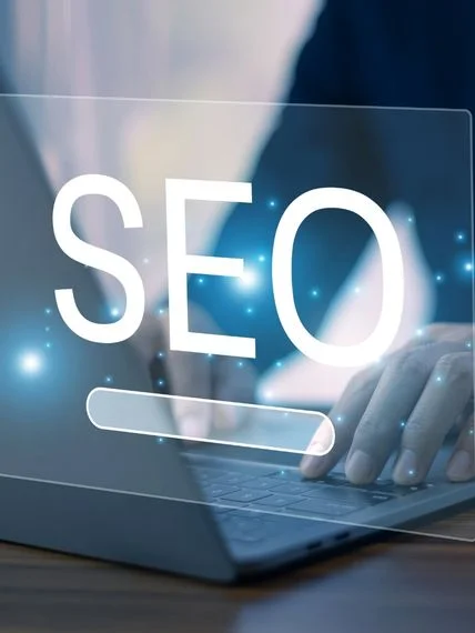 Person typing on a laptop behind a glowing SEO search bar graphic.
