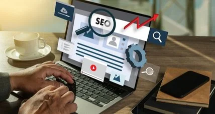 Laptop surrounded by SEO graphics, including a magnifying glass, search icons, and an upward trend arrow.