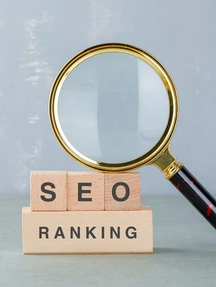 Wooden blocks spelling “SEO Ranking” beneath a gold magnifying glass.